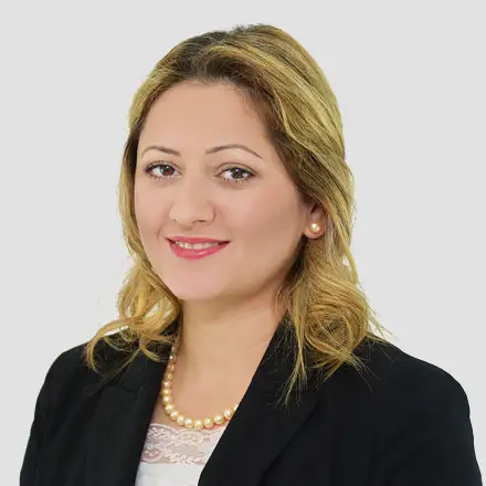 Woman with shoulder-length blonde hair wearing a black blazer, white top, pearl necklace, and pearl earrings, smiling against a plain light background—perfect for an Ashburn VA Optometrist or Eye Exam professional profile.